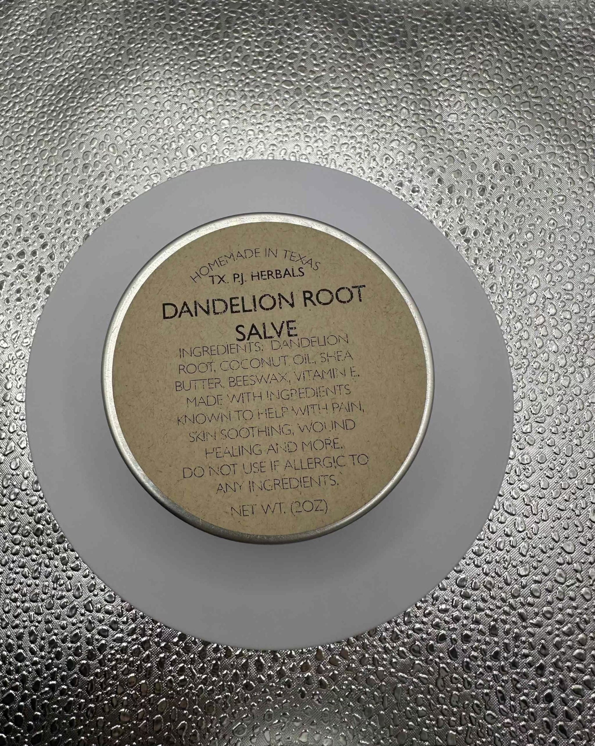 All-Natural Dandelion Root Salve in a jar with fresh dandelions and green leaves for natural skin care