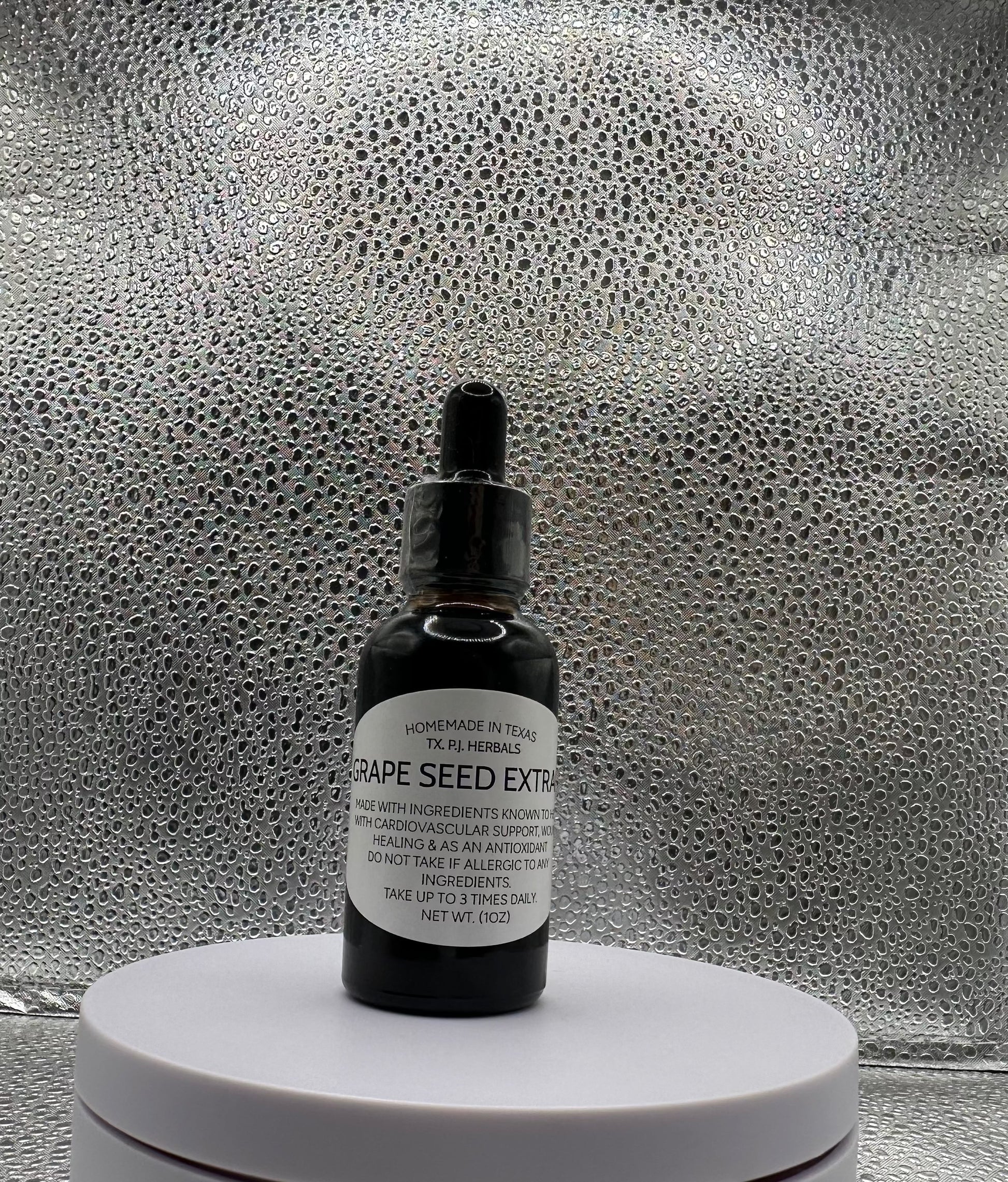 Bottle of all-natural grape seed tincture with fresh grapes and leaves